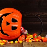 Halloween Jack o Lantern candy holder with spilling candy on rustic wood background